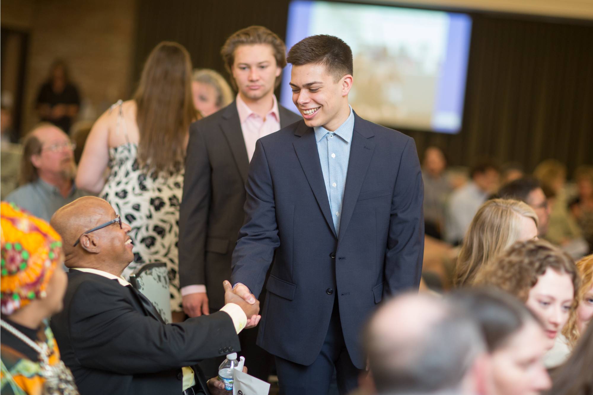 Smiling Honors graduate and supporter shaking hands.